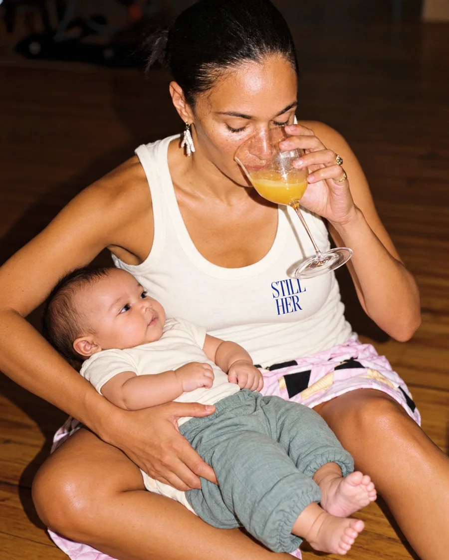 Mother enjoying orange juice with her baby in her arms